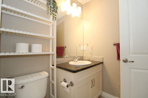 Well-lit bathroom featuring a white vanity with cabinet storage, a dark granite countertop, an undermount sink, and a large wall-mounted mirror - 3048 Harvey Crescent Nw, Edmonton, AB - Indoor Photo Showing Bathroom