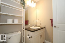 Well-lit bathroom featuring a white vanity with cabinet storage, a dark granite countertop, an undermount sink, and a large wall-mounted mirror - 