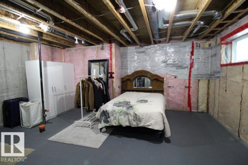 Unfinished basement area with exposed ceiling joists and ductwork, featuring insulated walls, a painted concrete floor, and a visible window opening - 3048 Harvey Crescent Nw, Edmonton, AB - Indoor Photo Showing Basement