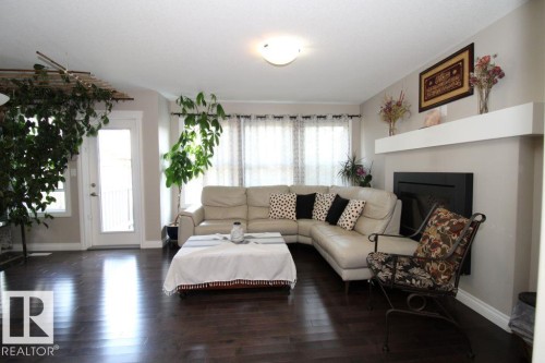 Living area featuring dark wood-finish flooring, a contemporary fireplace with a floating mantel, and a transom window above the exterior door - 3048 Harvey Crescent Nw, Edmonton, AB - Indoor Photo Showing Living Room With Fireplace