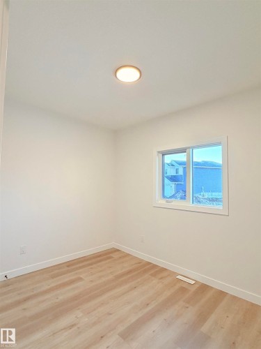 Neutral-toned room featuring a single window and wood-finish flooring - 3150 Magpie Way Nw, Edmonton, AB - Indoor Photo Showing Other Room