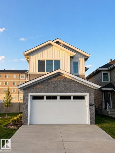 Contemporary two-story residence with a concrete driveway, attached garage featuring horizontal windows, and a stone facade accent - 3150 Magpie Way Nw, Edmonton, AB - Outdoor