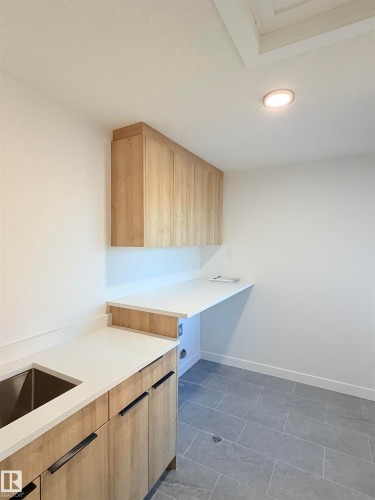 Light wood-finish cabinetry and white countertops, featuring an undermount sink and matte black hardware - 3150 Magpie Way Nw, Edmonton, AB - Indoor Photo Showing Kitchen