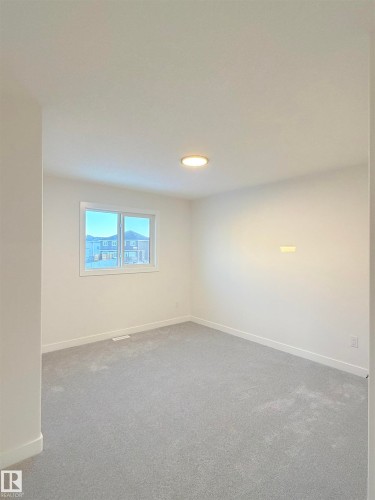 Spacious room featuring light gray carpeting, white painted walls, a single window, and a flush-mount ceiling light fixture - 3150 Magpie Way Nw, Edmonton, AB - Indoor Photo Showing Other Room