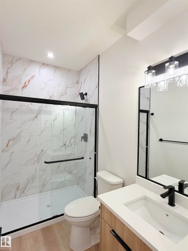 Modern bathroom featuring a walk-in shower with a black-framed glass enclosure, white and gray veined tile, and a recessed ceiling light - 3150 Magpie Way Nw, Edmonton, AB - Indoor Photo Showing Bathroom