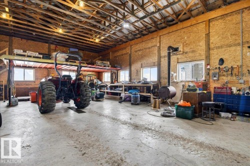 Spacious industrial workshop featuring exposed beam ceiling with skylights, brick and concrete block walls, concrete flooring, and ample room for equipment and storage - 531064 Range Road 174, Rural Lamont County, AB - Indoor Photo Showing Garage
