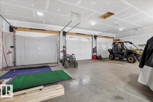 Spacious garage featuring multiple overhead door openings, polished concrete flooring, ceiling-mounted storage systems, and ample room for vehicles and equipment storage - 531064 Range Road 174, Rural Lamont County, AB - Indoor Photo Showing Garage