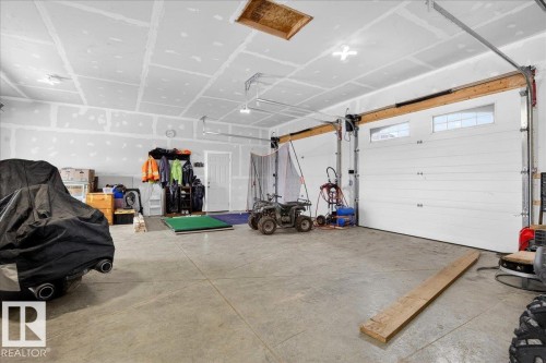 Spacious attached garage featuring concrete flooring, overhead door with automatic opener, wooden beam support structure, and ample storage potential with built-in shelving and wall-mounted organization systems - 531064 Range Road 174, Rural Lamont County, AB - Indoor Photo Showing Garage