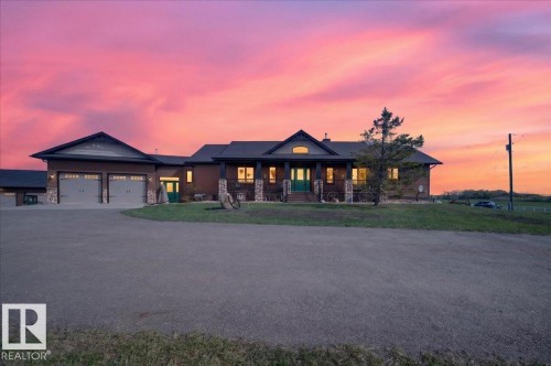 Stunning contemporary ranch home featuring a two-car attached garage, expansive front elevation with multiple gabled rooflines, and warm interior lighting that illuminates the open floor plan - 531064 Range Road 174, Rural Lamont County, AB - Outdoor With Deck Patio Veranda