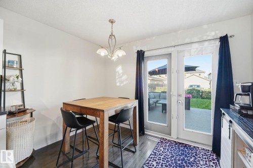 Dining area featuring dark wood-finish flooring, a contemporary chandelier, and white walls - 215 85 Street Sw, Edmonton, AB 
