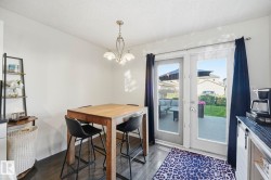 Dining area featuring dark wood-finish flooring, a contemporary chandelier, and white walls - 