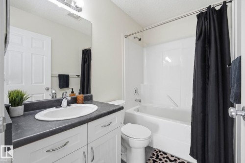 Bathroom featuring a white vanity with an oval undermount sink, dark countertop, and chrome fixtures - 215 85 Street Sw, Edmonton, AB 