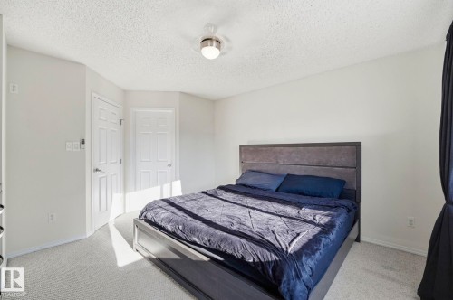 Bedroom featuring light-toned carpeting, white walls, and a textured ceiling - 215 85 Street Sw, Edmonton, AB 
