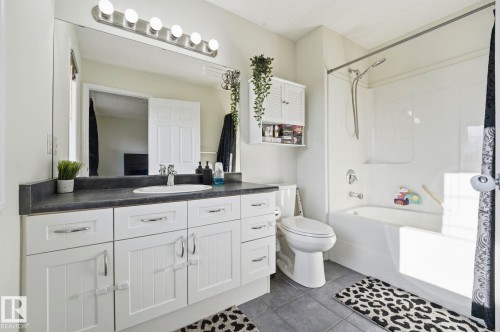 Modern bathroom featuring a single white vanity with an undermount sink, dark countertop, and brushed nickel hardware - 215 85 Street Sw, Edmonton, AB 