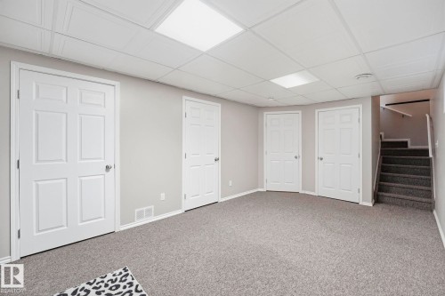 Spacious room featuring light gray walls, gray carpeting, and multiple white six-panel doors - 215 85 Street Sw, Edmonton, AB 