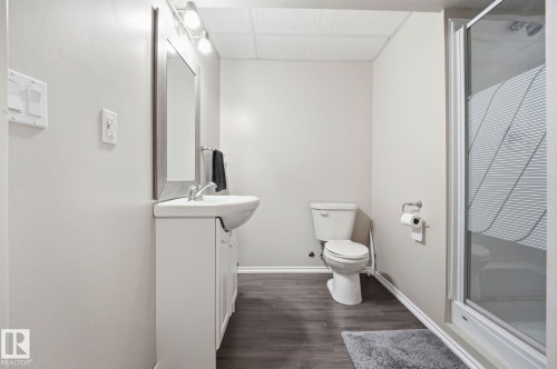 Bathroom featuring a vanity with integrated sink, chrome faucet, wall-mounted mirror, and overhead track lighting - 215 85 Street Sw, Edmonton, AB 