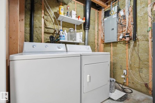 Utility area with a white washer and dryer pair, an electrical panel, and exposed wall insulation - 215 85 Street Sw, Edmonton, AB 