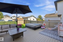Spacious outdoor deck featuring a hot tub, white railings, and direct access to a fenced yard with a manicured lawn - 