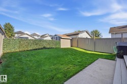 Expansive backyard featuring a lush lawn, concrete patio, and a light-toned wooden privacy fence - 