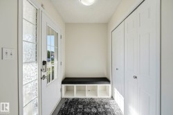 Entryway featuring a white paneled door with glass inserts, a built-in storage bench, and bi-fold closet doors - 