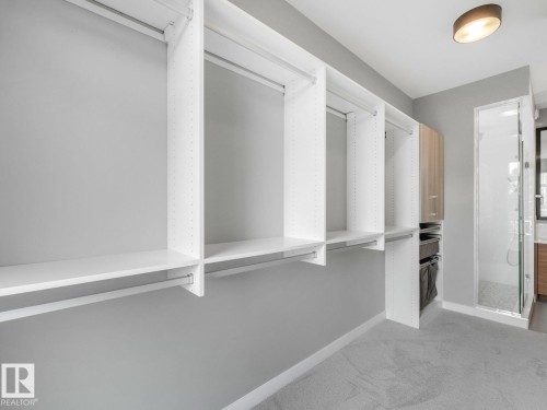 Custom closet system featuring white shelving and hanging rods - 11613 72 Avenue Nw, Edmonton, AB - Indoor
