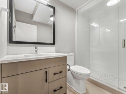 Contemporary bathroom featuring a neutral-toned vanity with black hardware, a rectangular undermount sink, and a framed mirror with integrated lighting - 