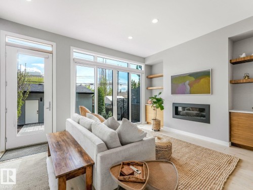 Living area featuring a sleek linear fireplace, light wood-finish flooring, and recessed lighting - 11613 72 Avenue Nw, Edmonton, AB - Indoor Photo Showing Living Room With Fireplace