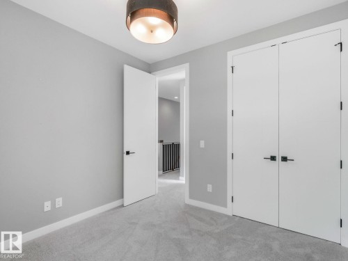 Neutral gray wall paint with white baseboards and light gray carpeting - 11613 72 Avenue Nw, Edmonton, AB - Indoor Photo Showing Other Room