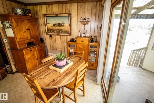 Dining area featuring wood-paneled walls and patterned flooring - 11218 Twp Rd 590, Rural St. Paul County, AB - Indoor Photo Showing Dining Room