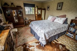 Bedroom featuring wood-finish flooring, a built-in wooden bookshelf, and a window with a roller shade - 