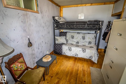 Hardwood flooring complements the gray paneled walls in this room, featuring a built-in bunk bed structure and a window with wood trim - 11218 Twp Rd 590, Rural St. Paul County, AB - Indoor