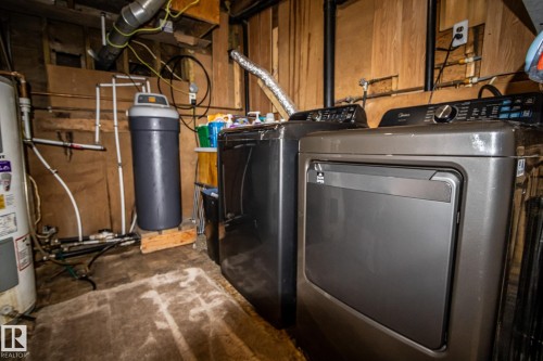 Dedicated utility space featuring a water heater, water filtration system, and two laundry appliances - 11218 Twp Rd 590, Rural St. Paul County, AB - Indoor Photo Showing Laundry Room
