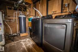 Dedicated utility space featuring a water heater, water filtration system, and two laundry appliances - 