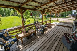Expansive covered porch featuring wood-finish decking, exposed wood beam framing, and a corrugated metal roof - 