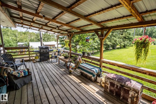 Expansive wood-finish deck featuring a metal roof covering, exposed wood beams, perimeter railing, and string lighting - 11218 Twp Rd 590, Rural St. Paul County, AB - Outdoor With Deck Patio Veranda With Exterior