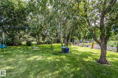 Expansive green lawn with mature trees and a dedicated garden area - 11218 Twp Rd 590, Rural St. Paul County, AB - Outdoor