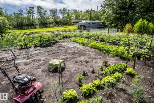 Garden area featuring cultivated planting beds, a white picket fence, and mature perimeter trees - 11218 Twp Rd 590, Rural St. Paul County, AB - Outdoor