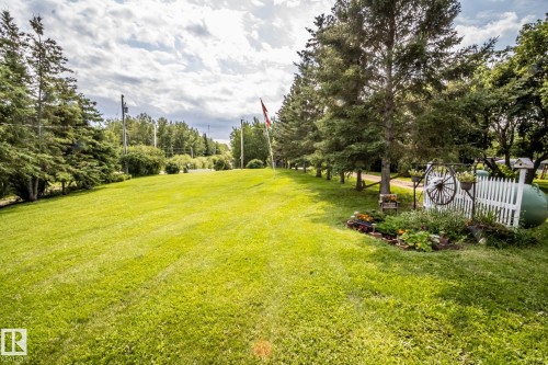 Expansive manicured lawn with mature tree-lined perimeter and white picket fencing - 11218 Twp Rd 590, Rural St. Paul County, AB - Outdoor