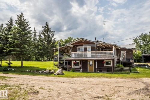 Wood-sided residence featuring an upper-level balcony with white railings, a covered lower-level porch, and a metal roof - 11218 Twp Rd 590, Rural St. Paul County, AB - Outdoor