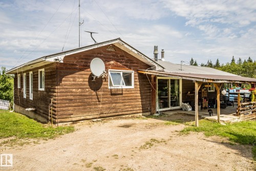 Rustic wood-sided exterior featuring a covered porch, sliding glass door, and multiple windows - 11218 Twp Rd 590, Rural St. Paul County, AB - Outdoor