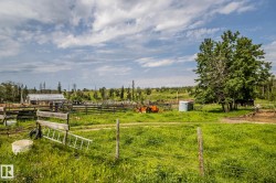Expansive rural property featuring a large field, mature trees, and a distant outbuilding - 