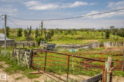 Expansive rural property featuring multiple functional outbuildings, sturdy post-and-rail fencing, and open pastureland with scattered mature tree coverage - 