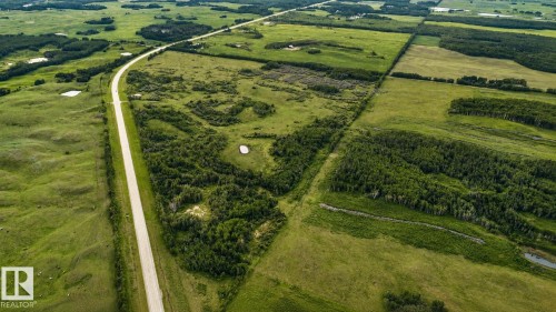 Expansive rural property featuring a paved road, natural ponds, and abundant tree cover - 11218 Twp Rd 590, Rural St. Paul County, AB - Outdoor With View