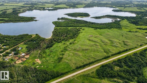 Expansive green landscape with a large body of water, bordered by dense woodlands and an arterial road - 11218 Twp Rd 590, Rural St. Paul County, AB - Outdoor With Body Of Water With View