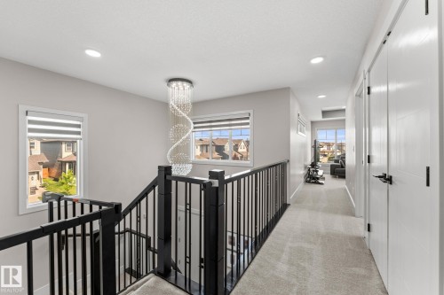 Second-floor hallway featuring black metal stair railings, recessed ceiling lighting, a decorative spiral pendant fixture, and polished concrete flooring - 12383 176 Avenue Nw, Edmonton, AB - Indoor Photo Showing Other Room