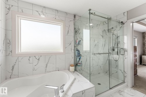 Bathroom featuring a corner soaking tub with deck-mounted chrome fixtures, a large frosted window, and an adjacent glass-enclosed shower with subway-tiled walls - 12383 176 Avenue Nw, Edmonton, AB - Indoor Photo Showing Bathroom