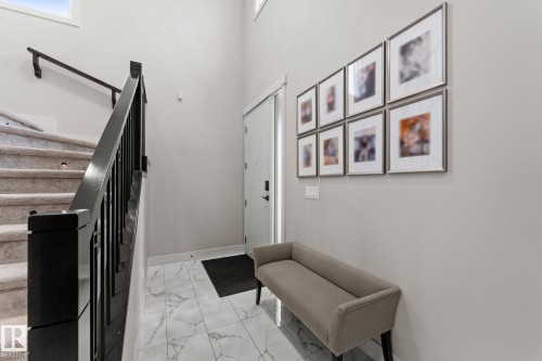 Welcoming entryway featuring marble-pattern tile flooring, neutral wall finishes, and a custom framed gallery wall displaying six coordinating art pieces - 12383 176 Avenue Nw, Edmonton, AB - Indoor Photo Showing Other Room