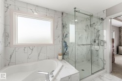 Bathroom featuring a corner soaking tub with deck-mounted chrome fixtures, a large frosted window, and an adjacent glass-enclosed shower with subway-tiled walls - 