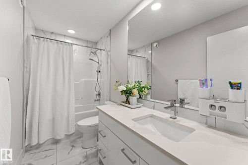 Contemporary bathroom featuring a white vanity with integrated sink, chrome faucet, and expansive wall mirror - 12383 176 Avenue Nw, Edmonton, AB - Indoor Photo Showing Bathroom