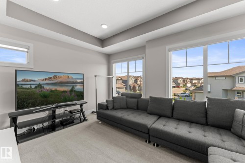 Spacious room with light gray walls, plush carpeting, large windows, and a tray ceiling with recessed lighting - 12383 176 Avenue Nw, Edmonton, AB - Indoor Photo Showing Living Room